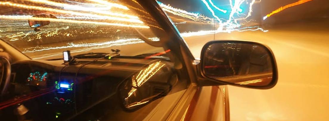 Vista lateral de un coche bajo unas líneas de luces en la carretera