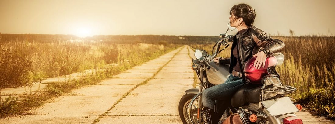 mujer sentada en una moto mirando al horizonte
