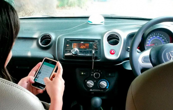 Mujer dentro de un coche consultando en el móvil apps para comprar coche