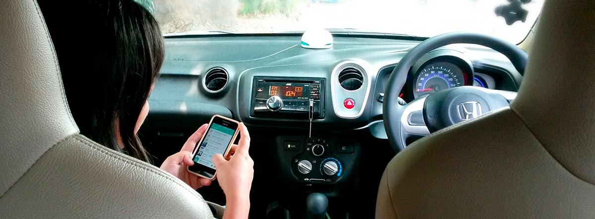 Mujer dentro de un coche consultando en el móvil apps para comprar coche
