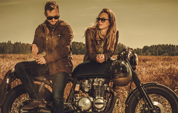 Hombre y mujer apoyados en una moto clásica