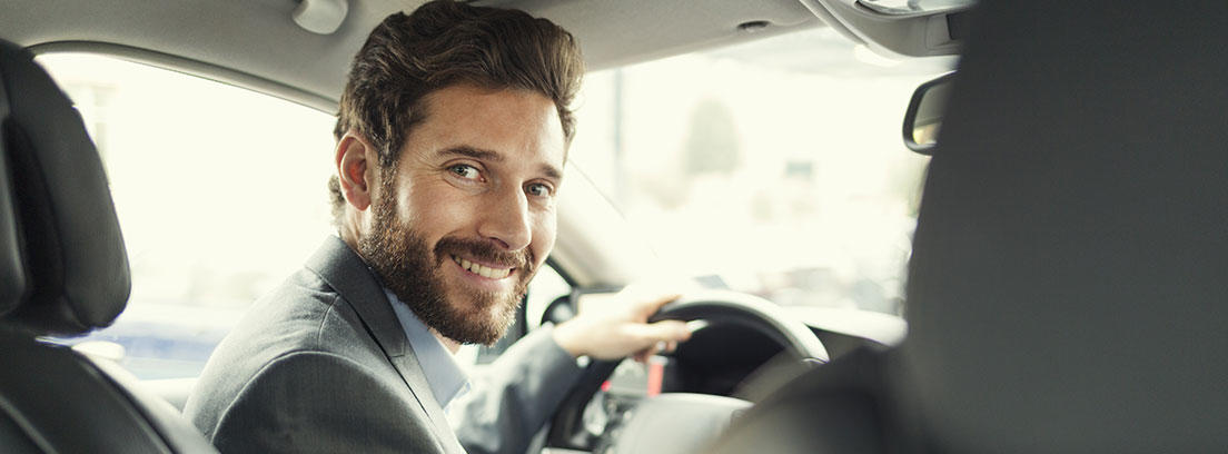 Hombre con barba y traje posa para una foto dentro del vehículo