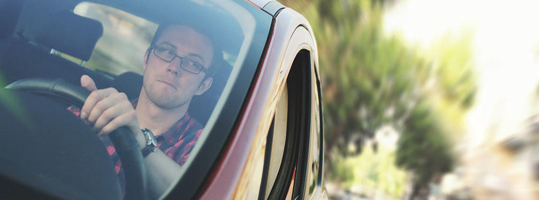 Hombre con gafas dentro e coche con una mano sobre volante