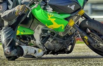 Motorista con casco sobre moto verde que inclina.