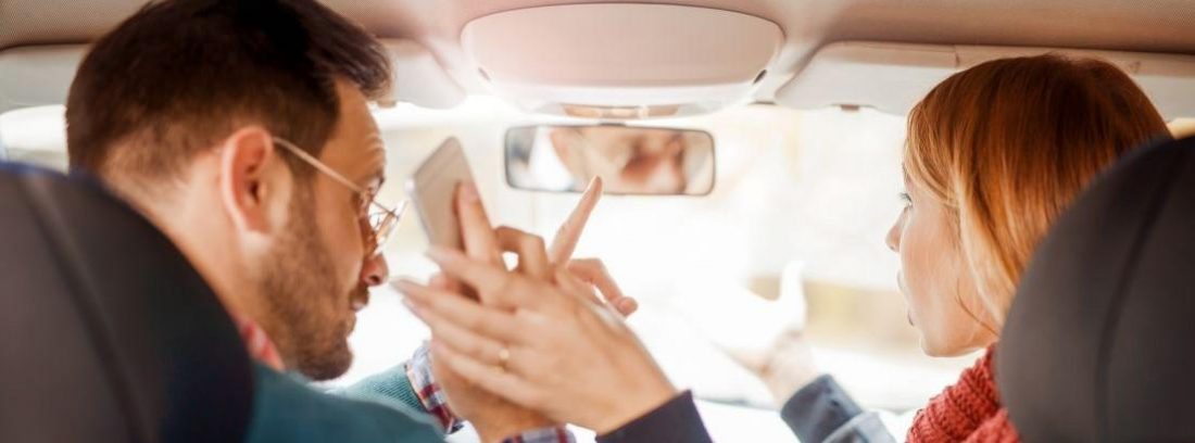 pareja discutiendo en un coche y un móvil en la mano