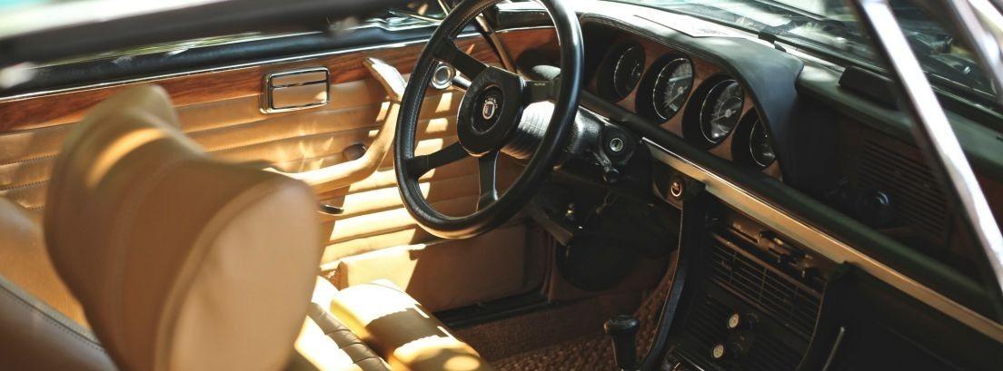 Diseño interior de coche con asientos de cuero y salpicadero de color madera.