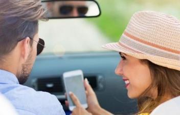 Mujer al volante de un coche y hombre al lado con teléfono móvil
