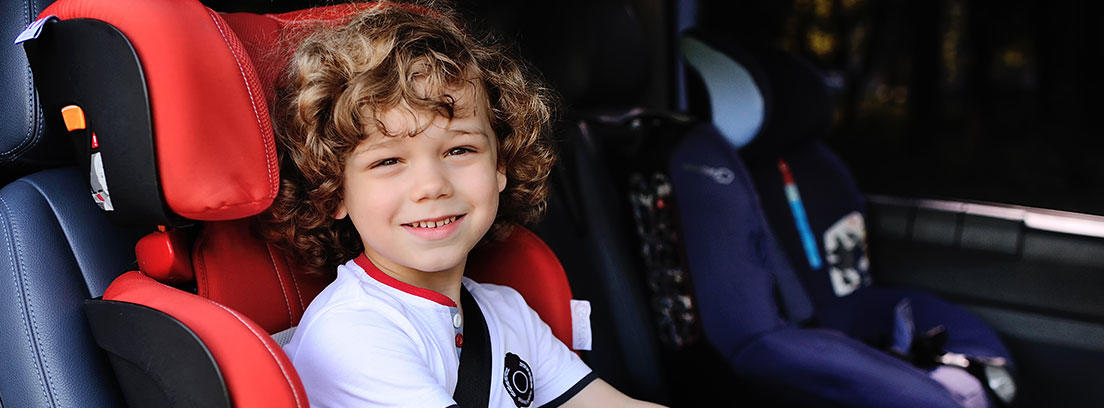 Niño sentado en silla de coche roja con cinturón de seguridad puesto