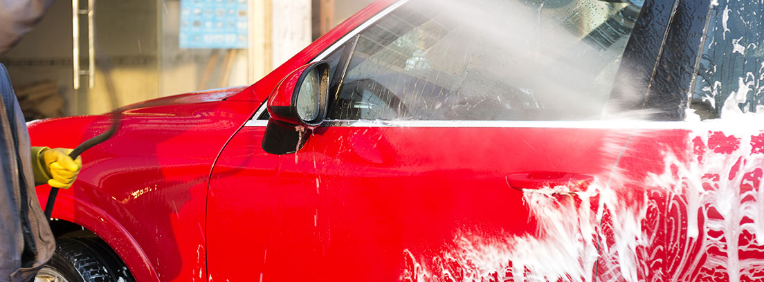 conductor limpiando la puerta de su coche rojo