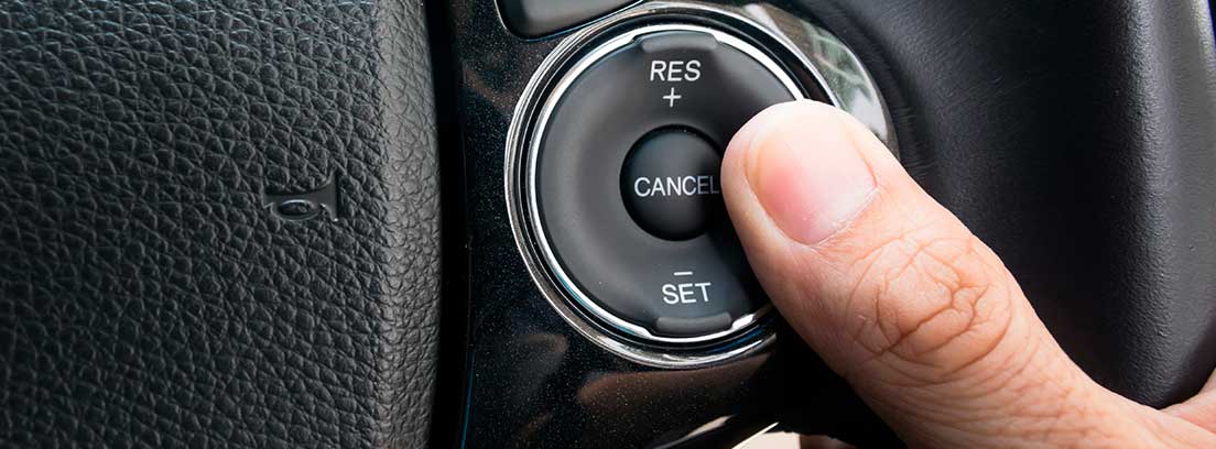 Una mano presiona los botones de control de velocidad en el volante de un coche