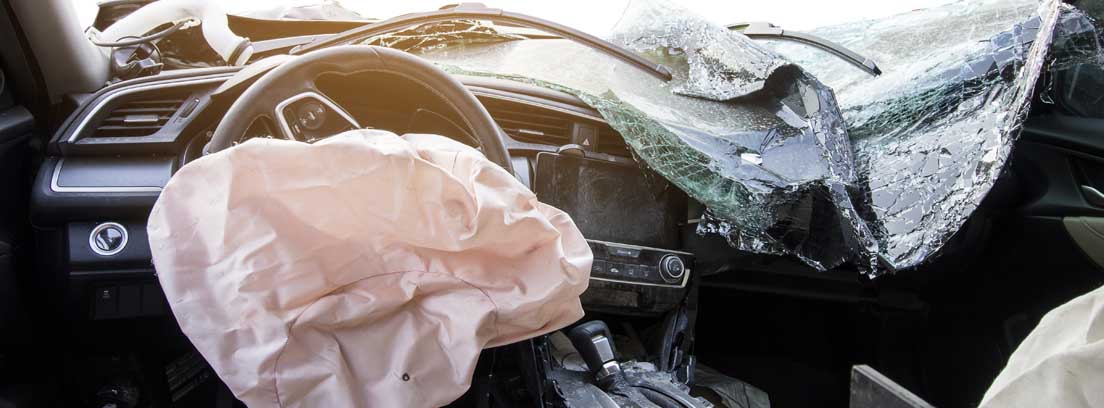 Interior de un coche con la luna rota y el airbag deshinchado tras una colisión