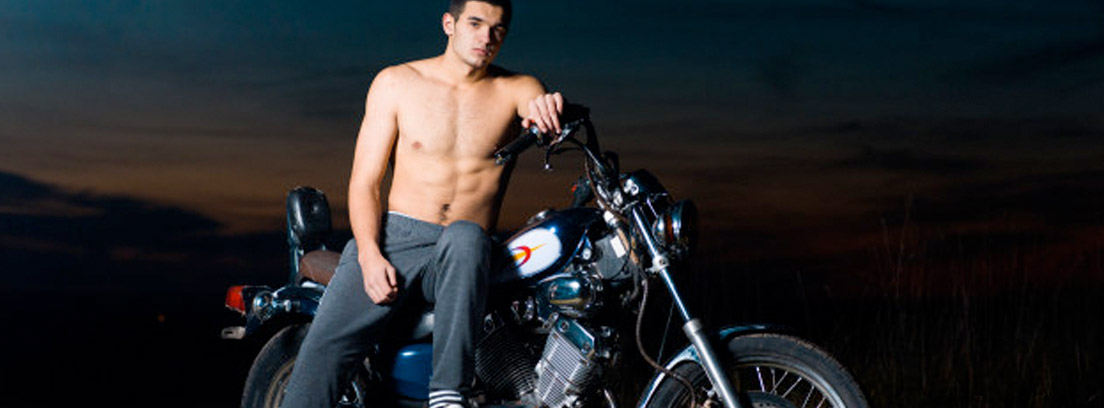 chico sin camiseta posando junto a una moto