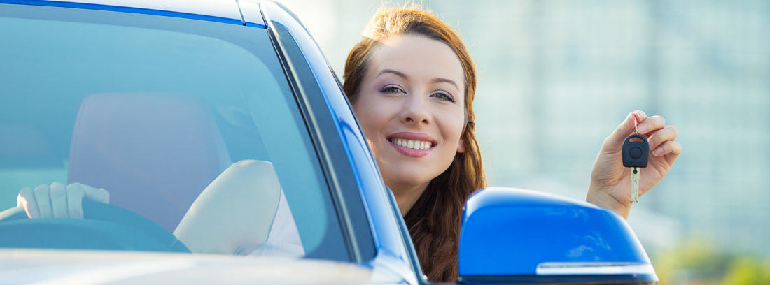 Mujer sonriente asomándose por la ventanilla de un coche con las llaves en la mano