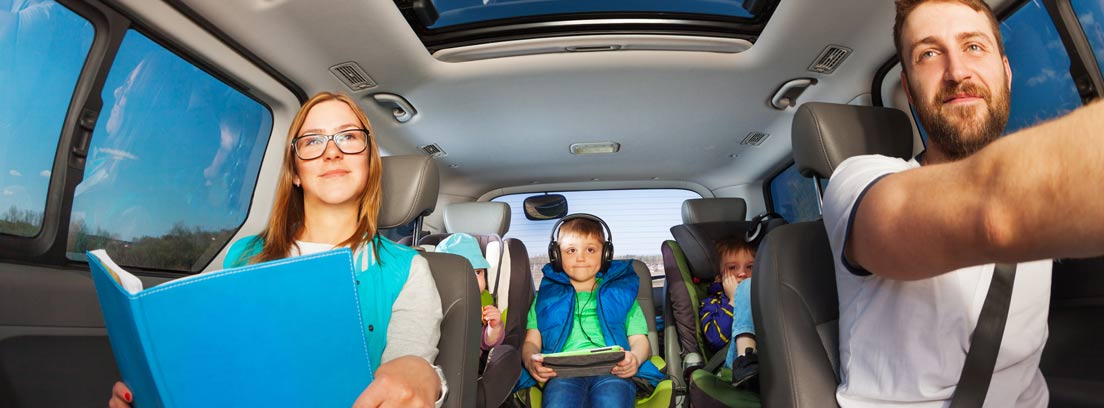 Hombre, mujer y niños acomodados en el interior de un vehículo espacioso.