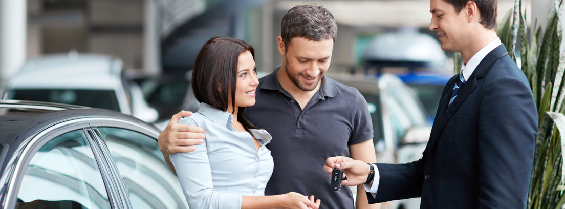 Hombre y mujer miran documentación de un coche en concesionario