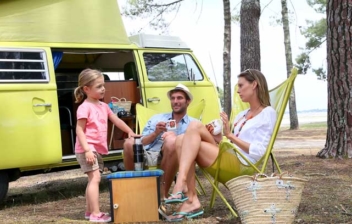 Familia sentada en el exterior de una furgoneta camper
