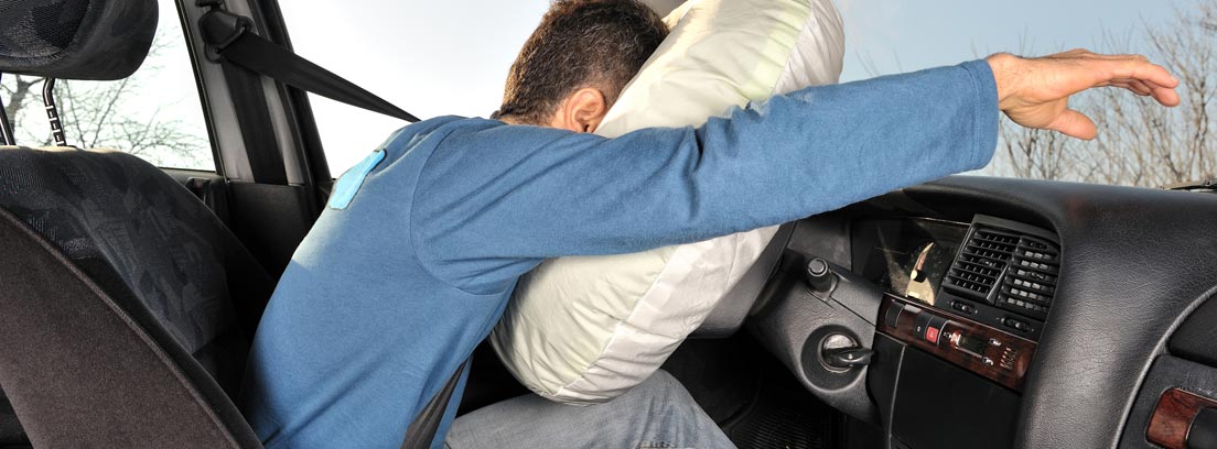 Hombre dentro de un coche con la cabeza apoyada en el airbag del volante
