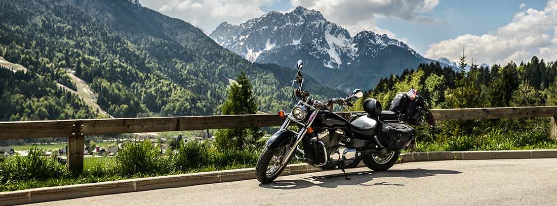 Moto apoyada en barrera de madera en carretera de montaña