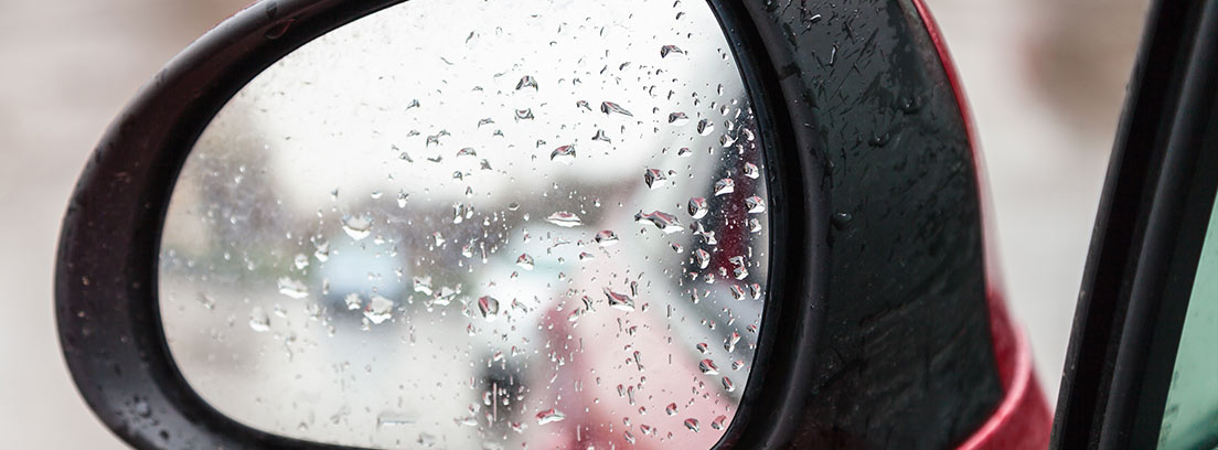 Espejo retrovisor de coche con gotas de lluvia.