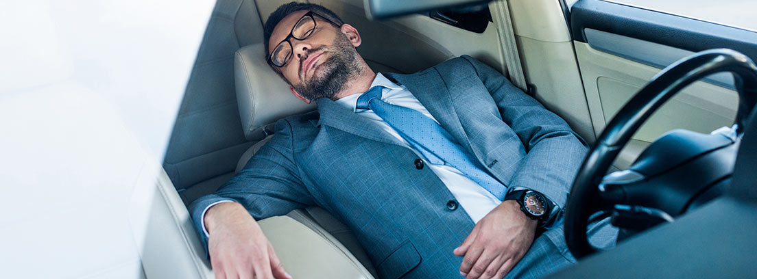 Hombre con traje durmiendo en el interior de su coche
