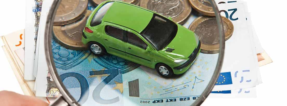 Lupa sobre un coche de juguete verde y billetes y monedas de euro