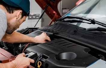 Hombre usando un voltímetro para comprobar el voltaje de la batería de un coche