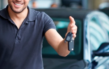 Hombre mostrando las llaves de un coche nuevo