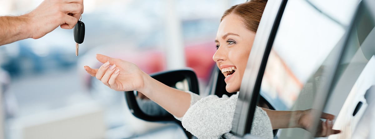 Mujer sonriente cogiendo las llaves de un coche