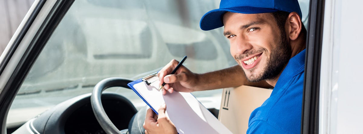 Hombre sonriente tomando notas sobre el volante de un camión