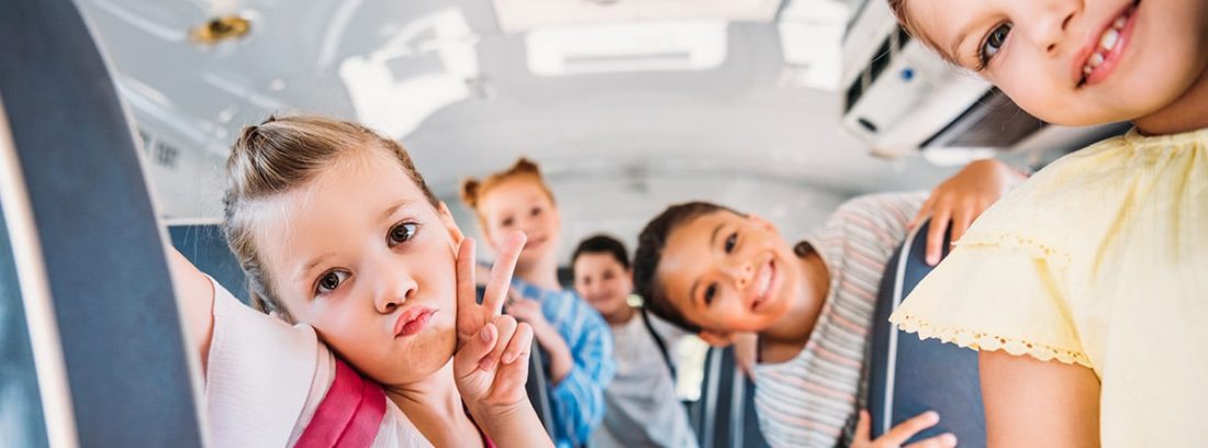 Niños sonrientes dentro de un autobús escolar