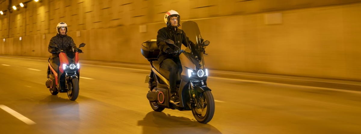 dos personas en sus motos Seat Mó eScooter 125 en la calle por la noche