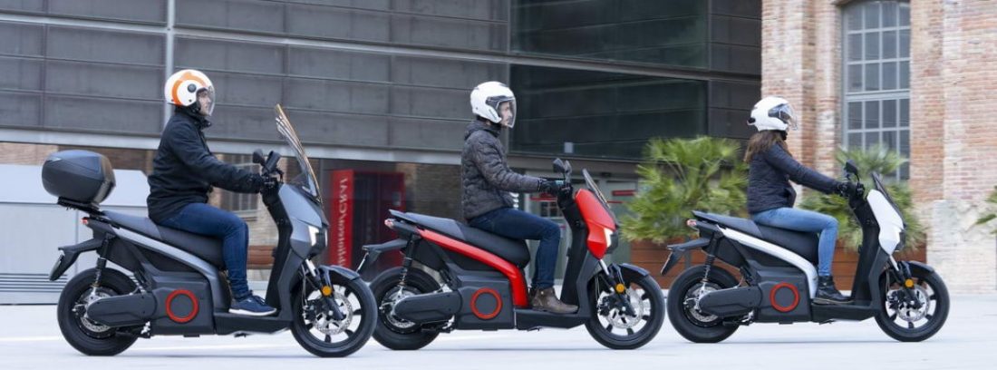 tres personas en sus motos Seat Mó eScooter 125 en la calle
