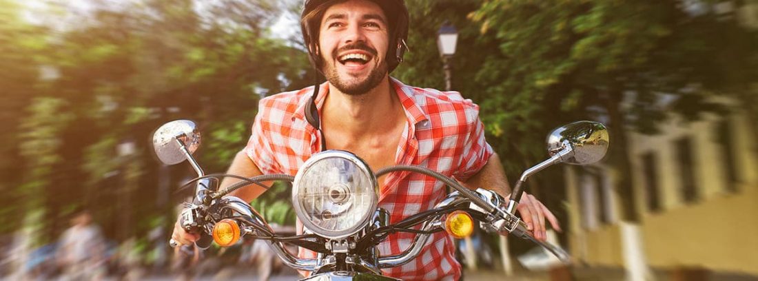 Hombre sonriente conduciendo una motoneta
