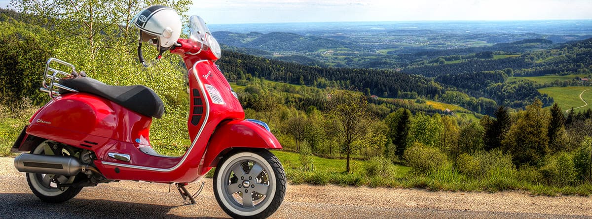 Motoneta o scooter rojo con paisaje al fondo