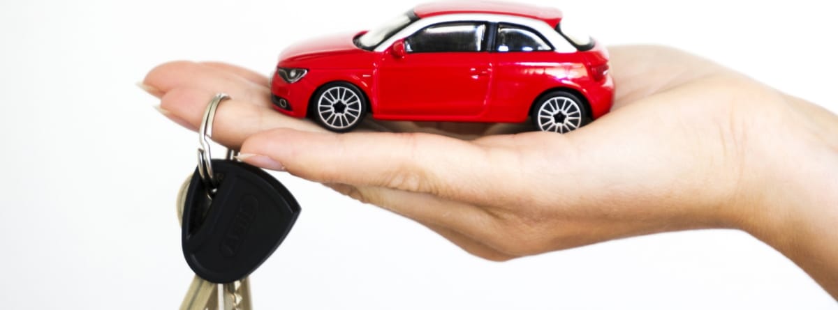 mano con un coche de juguete rojo y unas llaves de coche