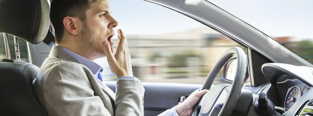 hombre bostezando en el coche mientras conduce