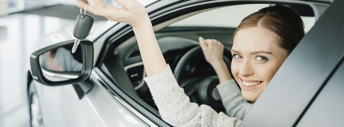 Mujer en un coche mostrando las llaves por la ventanilla