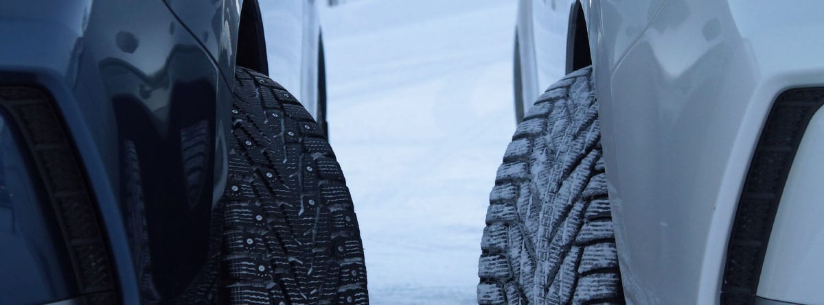 Primer plano de dos neumáticos con clavos en la nieve