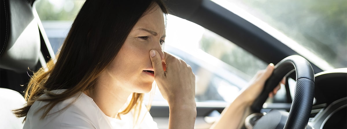 Mujer tapándose la nariz dentro de un coche