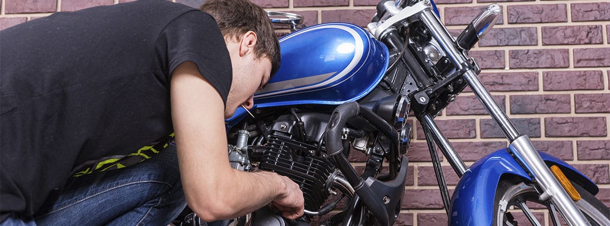 Hombre revisando un desperfecto en una moto