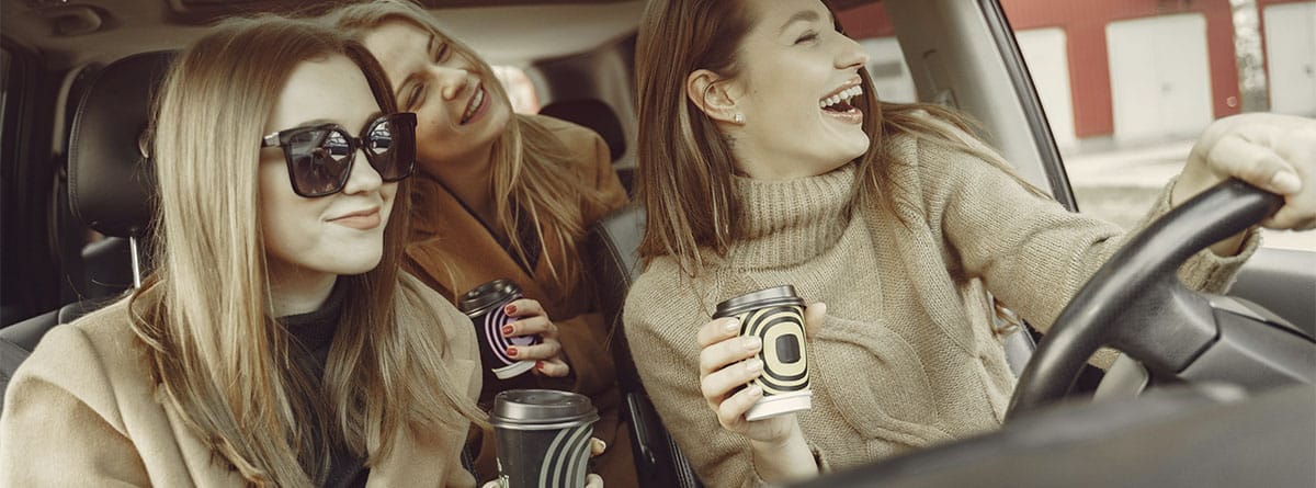 Mujeres bebiendo café en un coche
