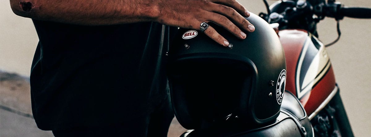 Hombre apoyando un casco sobre el asiento de una moto