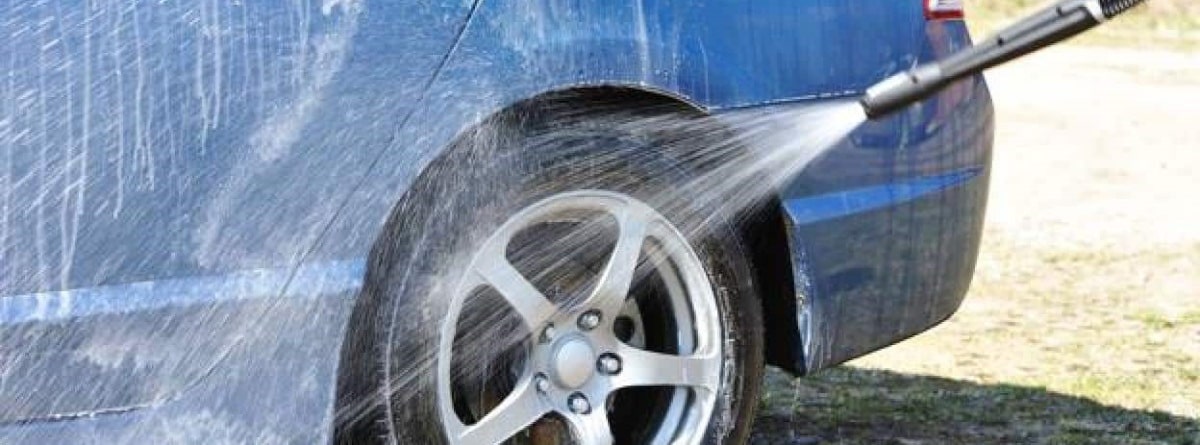 Pistola de lavado mojando un coche