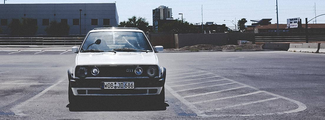 Coche blanco Golf GTI aparcado en parking vacío