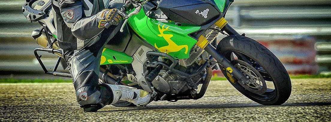 Motorista con casco sobre moto verde que inclina.