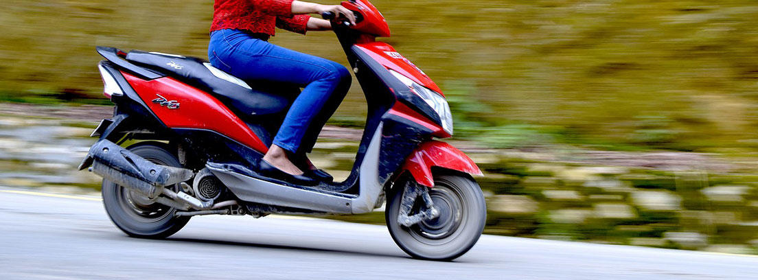 Mujer sobre moto scooter roja.