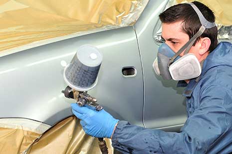 empleo sector automocion un hombre pintando un coche con spray en un taller