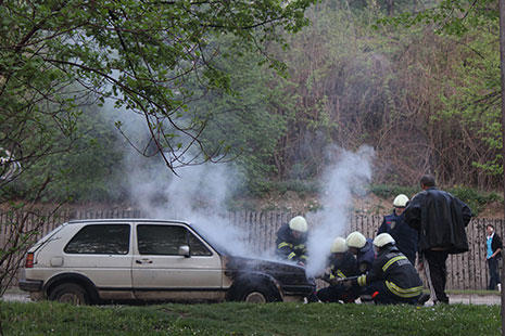 coche antiguo saliendo humo del capó y los bomberos apagando fuego