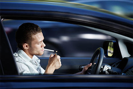 chico dentro del coche encendiendo un cigarro