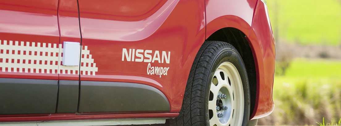 Detalle de la puerta y una rueda de una camper de Nissan
